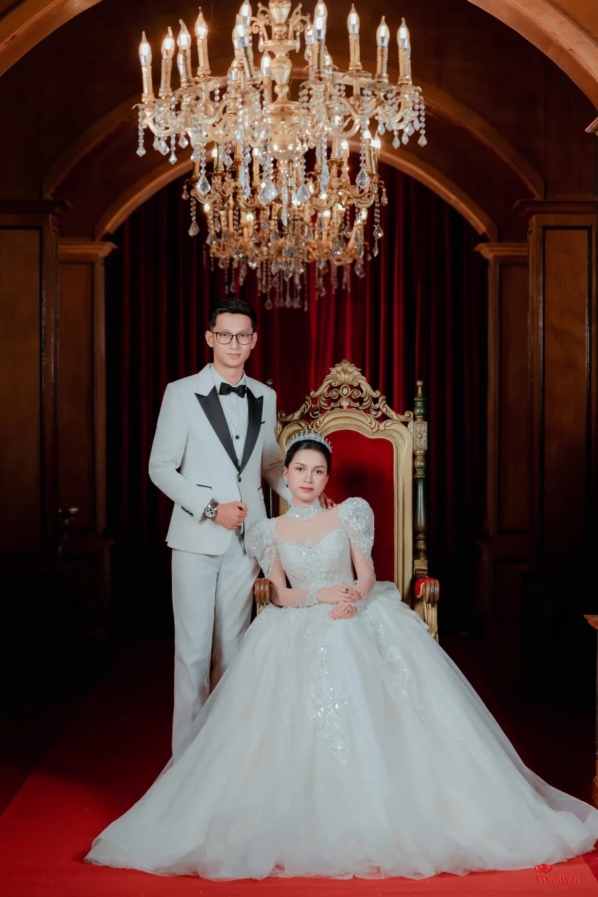 Hnin seated beneath a chandelier with Aung beside her