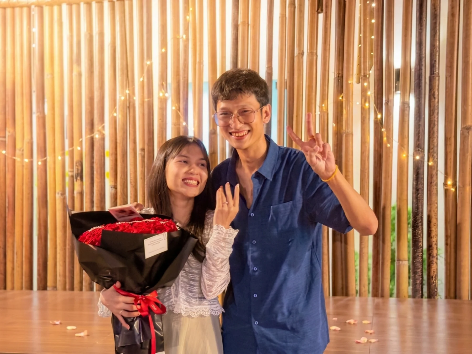Hnin showing her engagement ring beside Aung, holding red roses